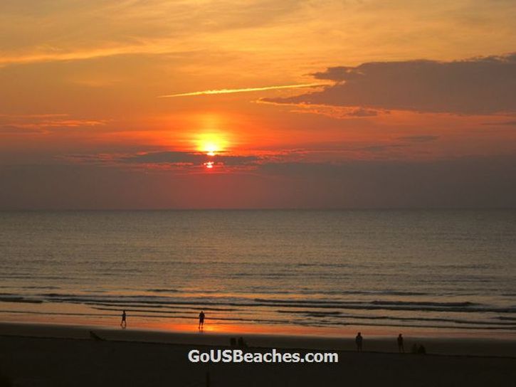 Colorful Cocoa Beach Florida Sunrise over Atlantic Ocean with red clouds and reflection on beach