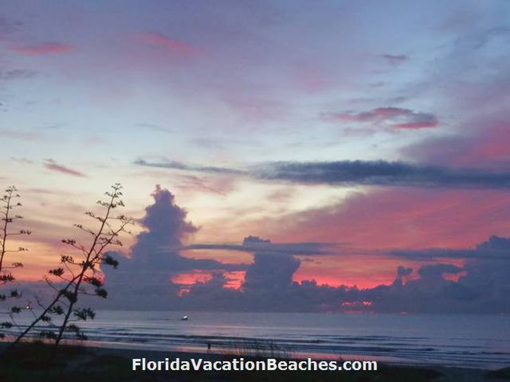 Colorful Cocoa Beach Florida Ocean Sunrise over Atlantic Ocean with clouds and a small boat going by